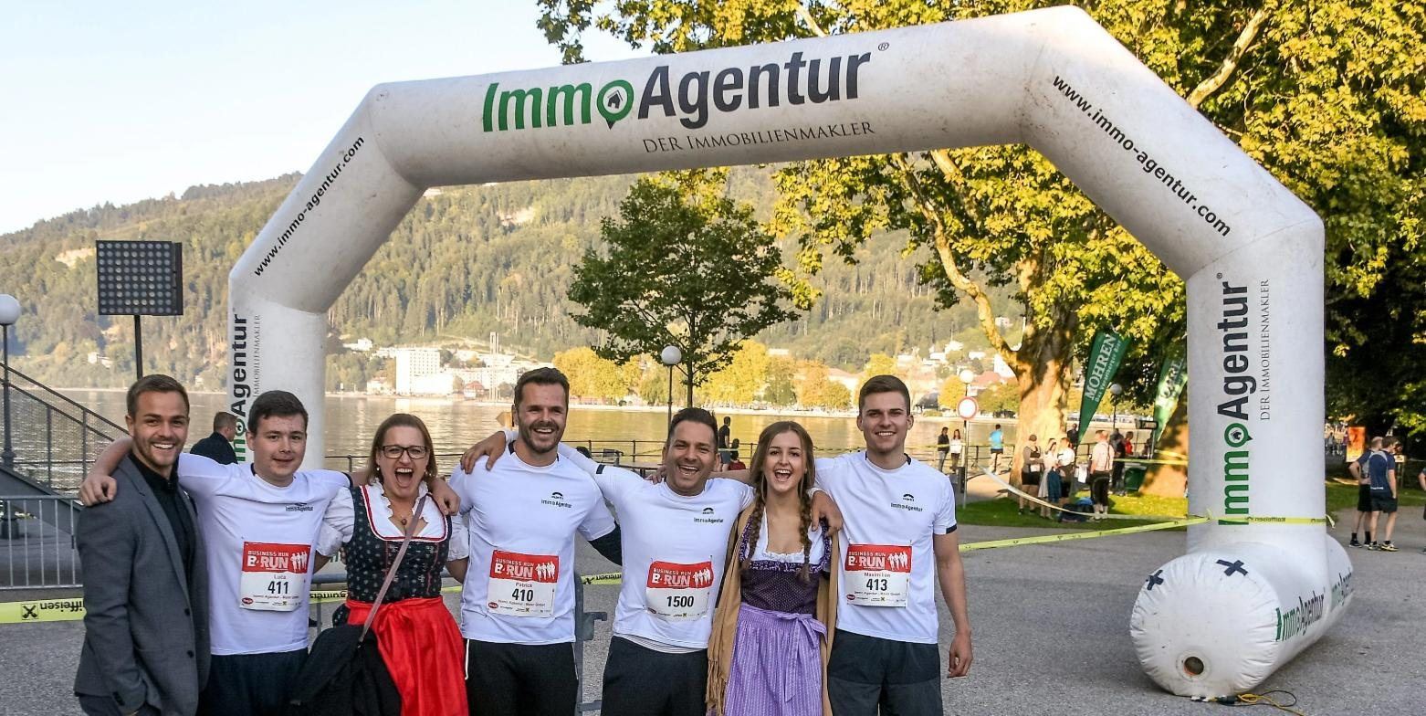 Team der ImmoAgentur in Laufshirts vor dem ImmoAgentur-Zielbogen am Bodenseeufer